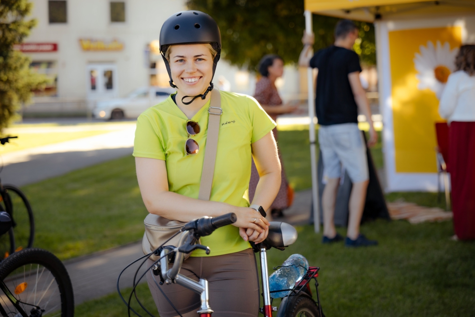 Sieviete velosipēda ķiverē stāv pie velosipēda