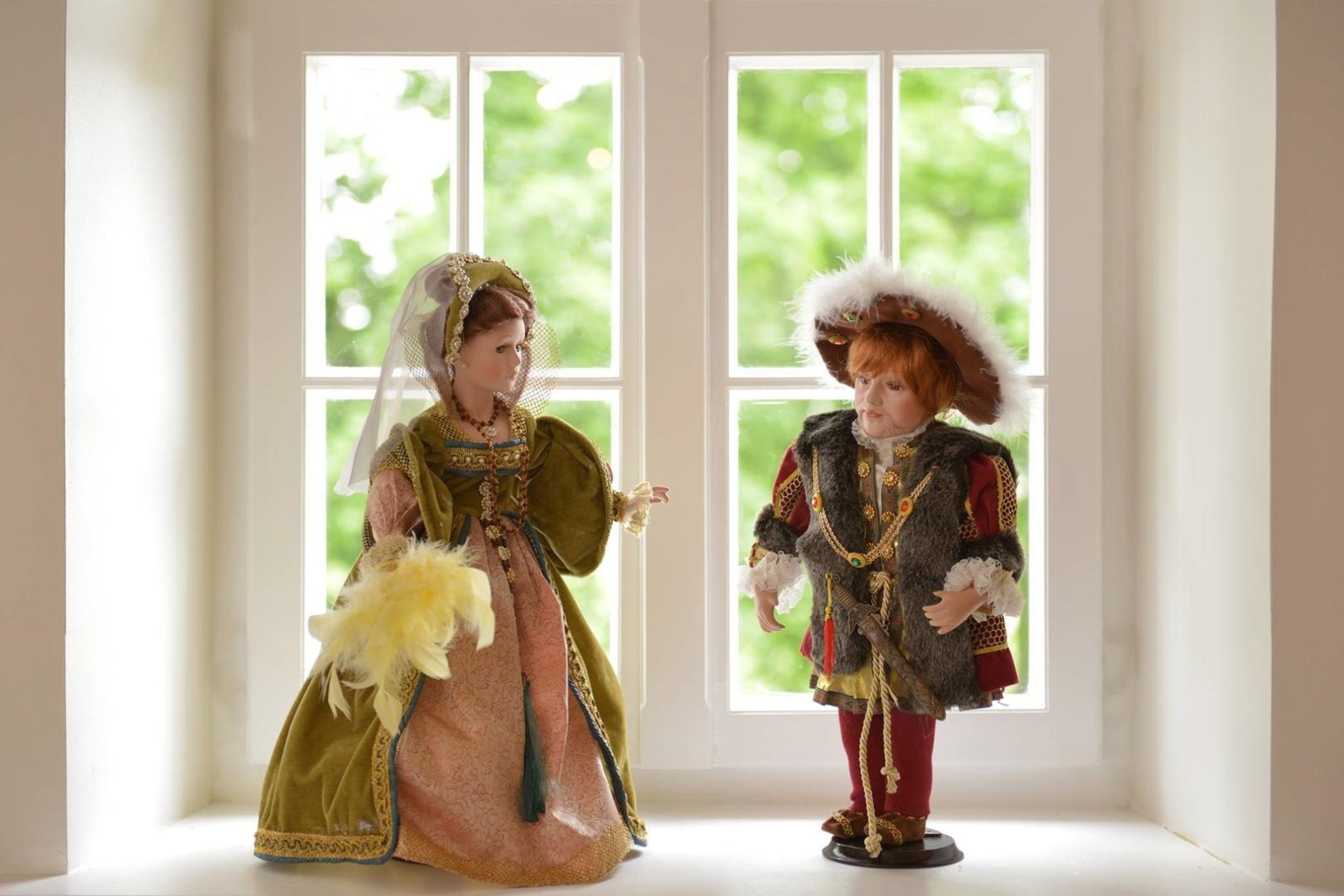 Divas porcelāna lelles pie loga