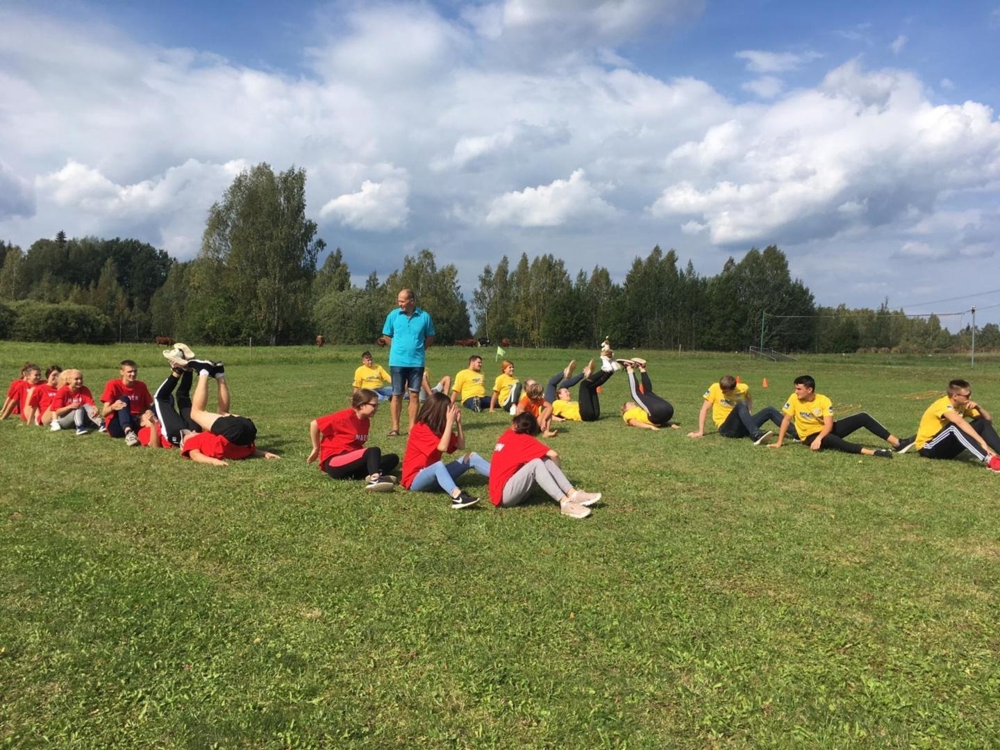 Cilvēku grupa vingro pļavā