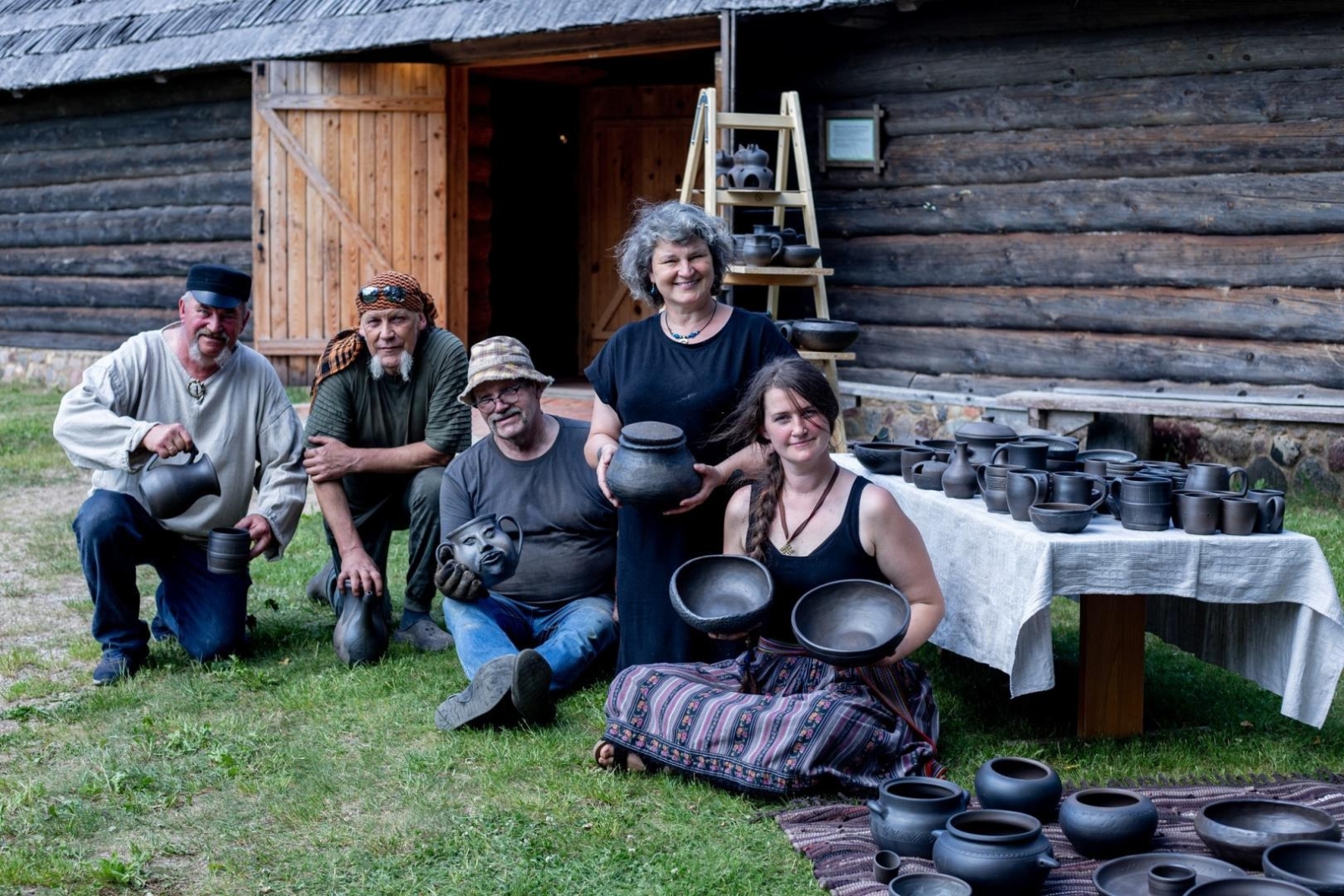 Cilvēku grupa pie lauku sētas