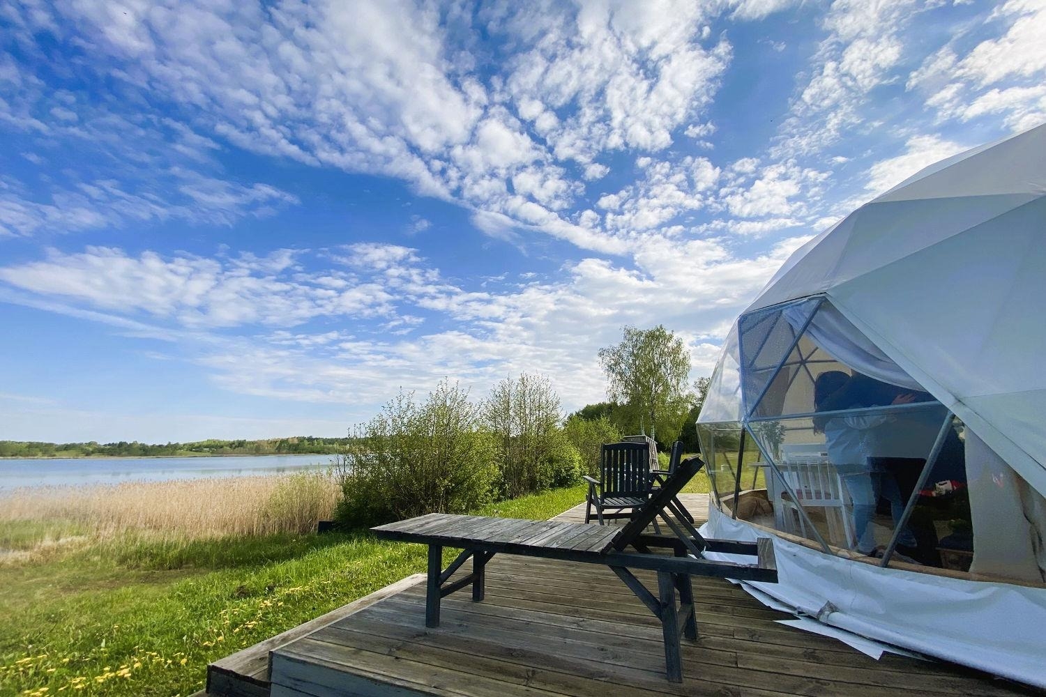 Glampinga kupols ar terasi pie ezera