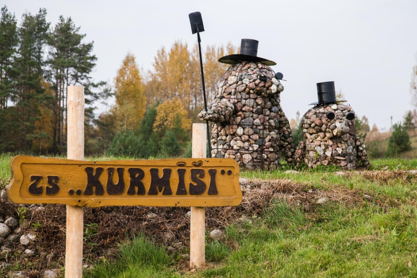 Izkārtne “ZS KURMĪŠI” pie akmens skulptūrām