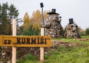 Izkārtne “ZS KURMĪŠI” pie akmens skulptūrām